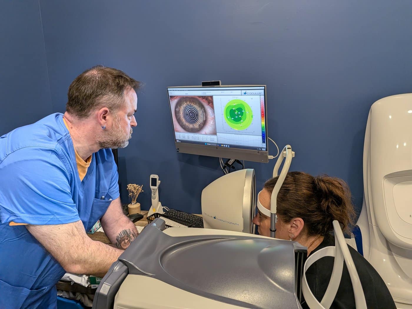 A COVE technician performing a corneal topography scan, with the resulting elevation map displayed on screen