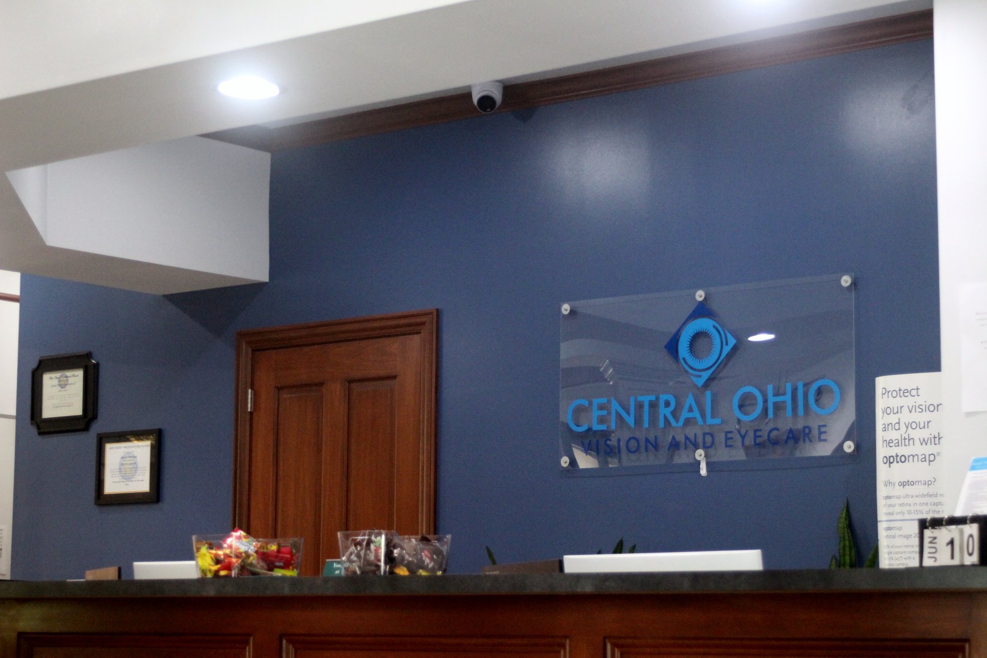 Front desk at Central Ohio Vision and Eyecare in New Albany with the practice logo on the wall