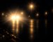 Illustration of a wet street at night where oncoming headlights and streetlights flare into starbursts and the road is hard to make out.